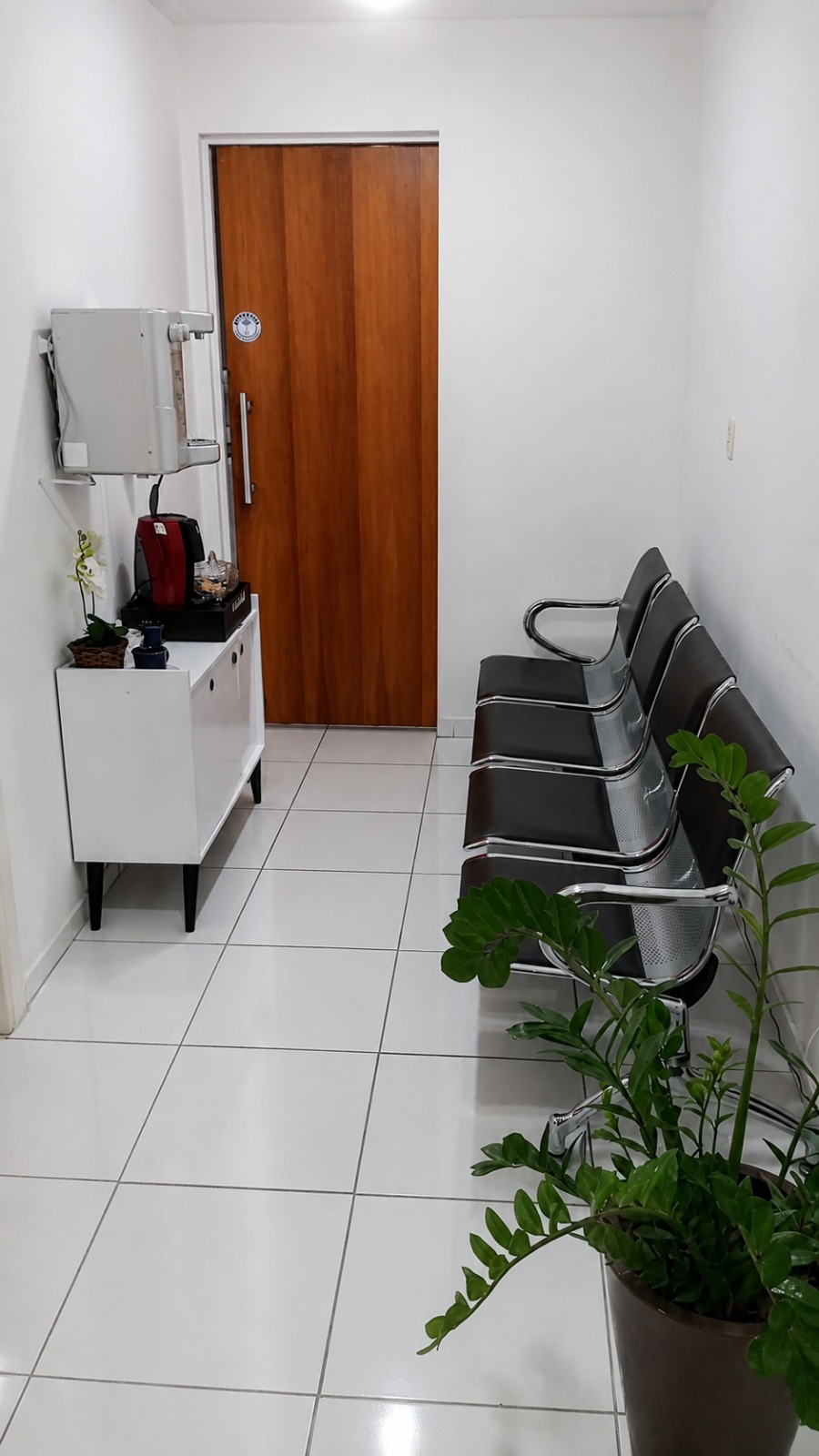 Recepção da clínica, com poltronas e água disponível para quem aguarda